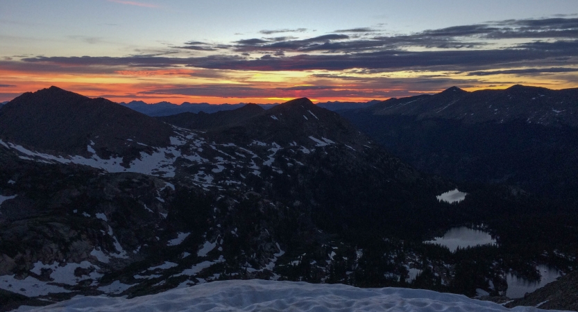 the sun is rising, illuminating snowy mountains at dawn